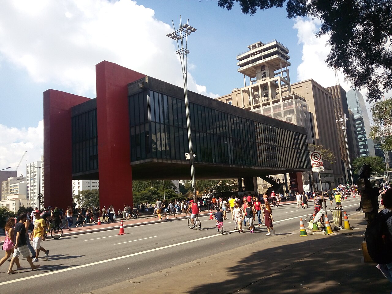Vista exterior del MASP con sus apoyos rojos y peatones en la avenida Paulista